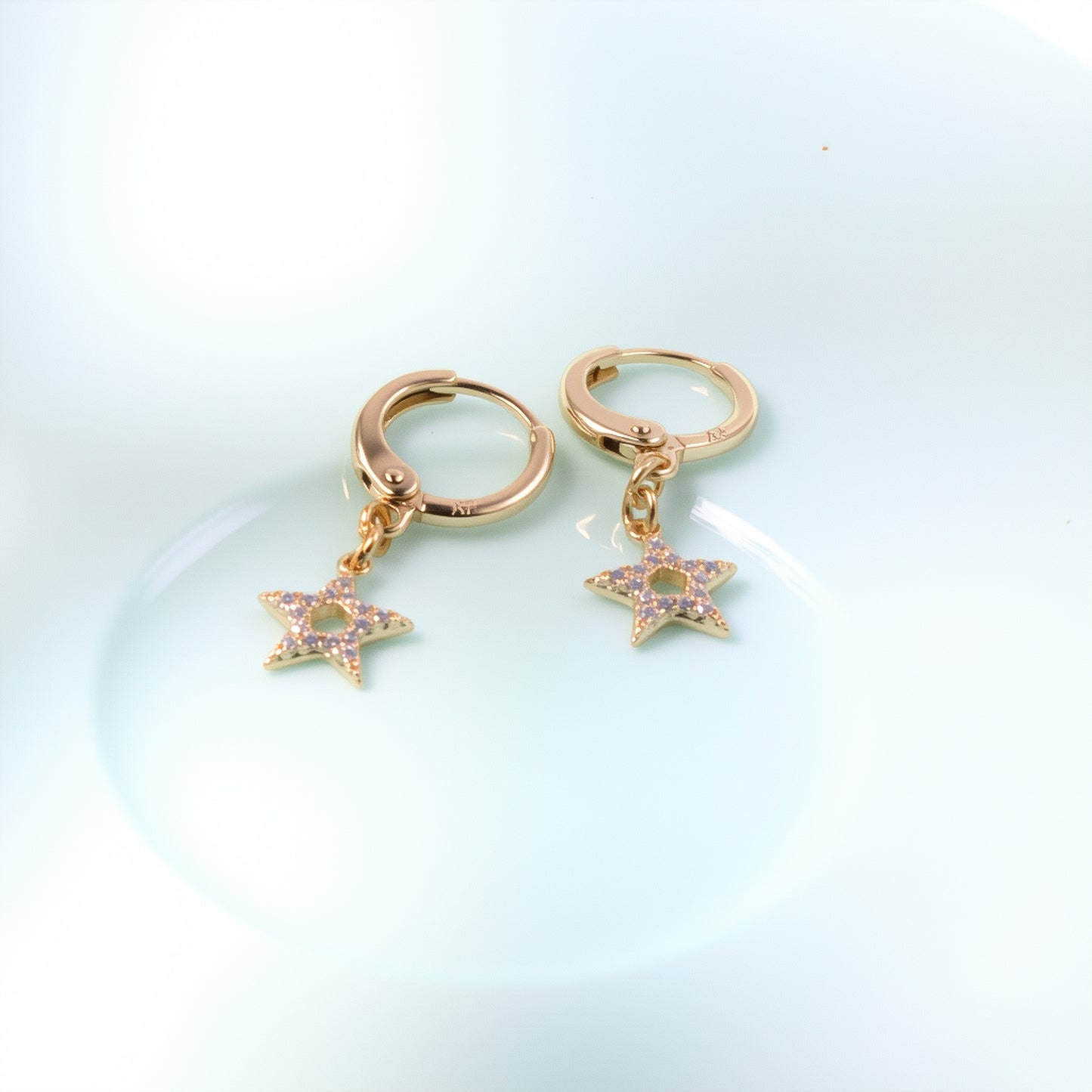 Delicate 14K gold huggie hoop earrings with a mini dangling star charm