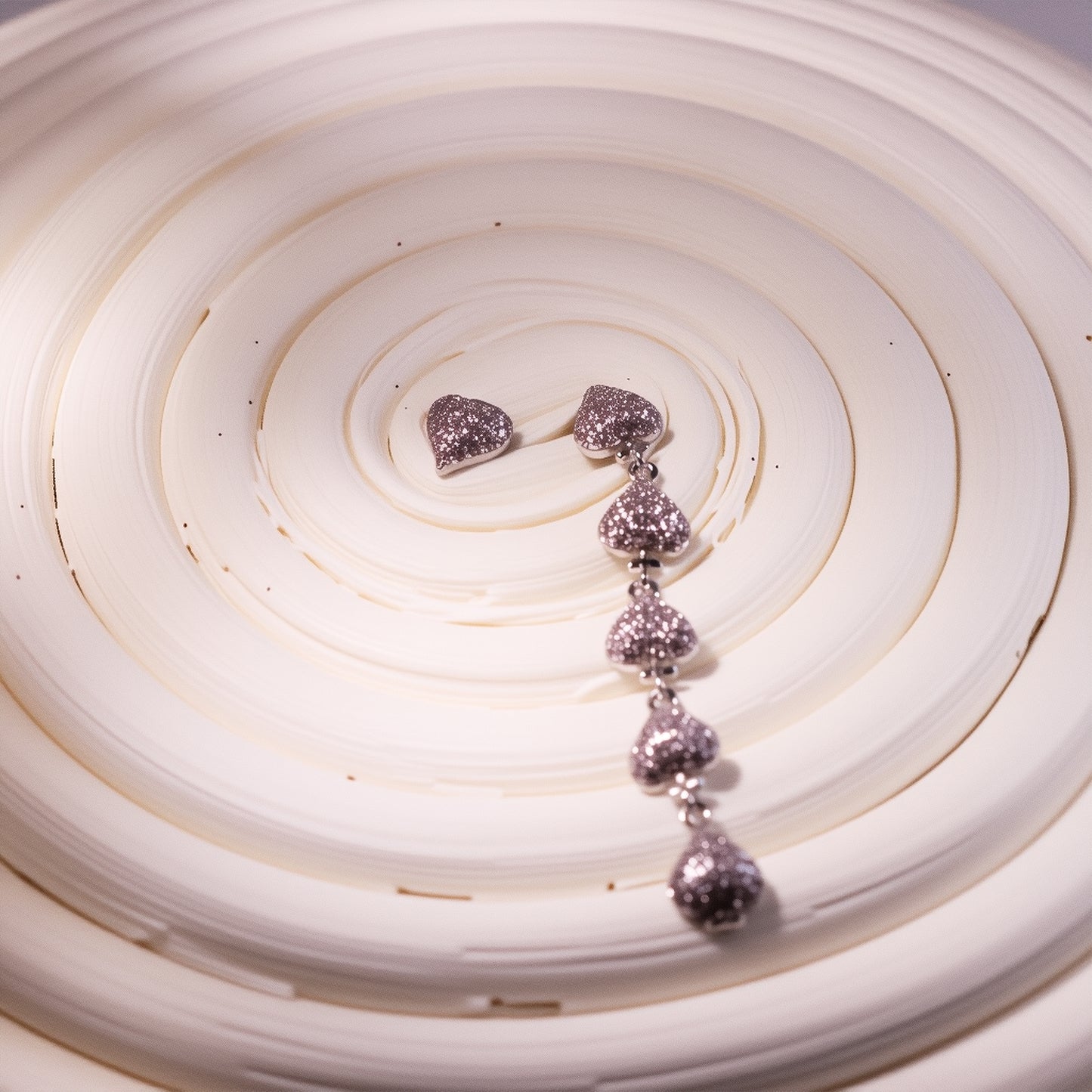 Gold plated asymmetric heart dangle earrings with zircon clusters, showcasing one solid heart and one clustered heart design on a model.