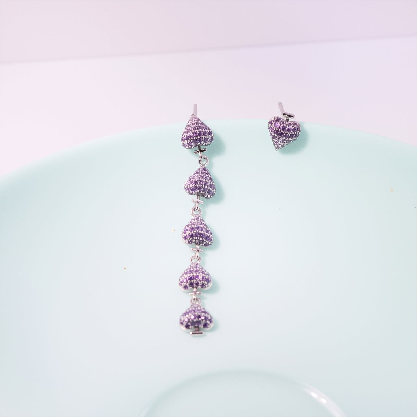 Gold plated asymmetric heart dangle earrings with zircon clusters, showcasing one solid heart and one clustered heart design on a model.