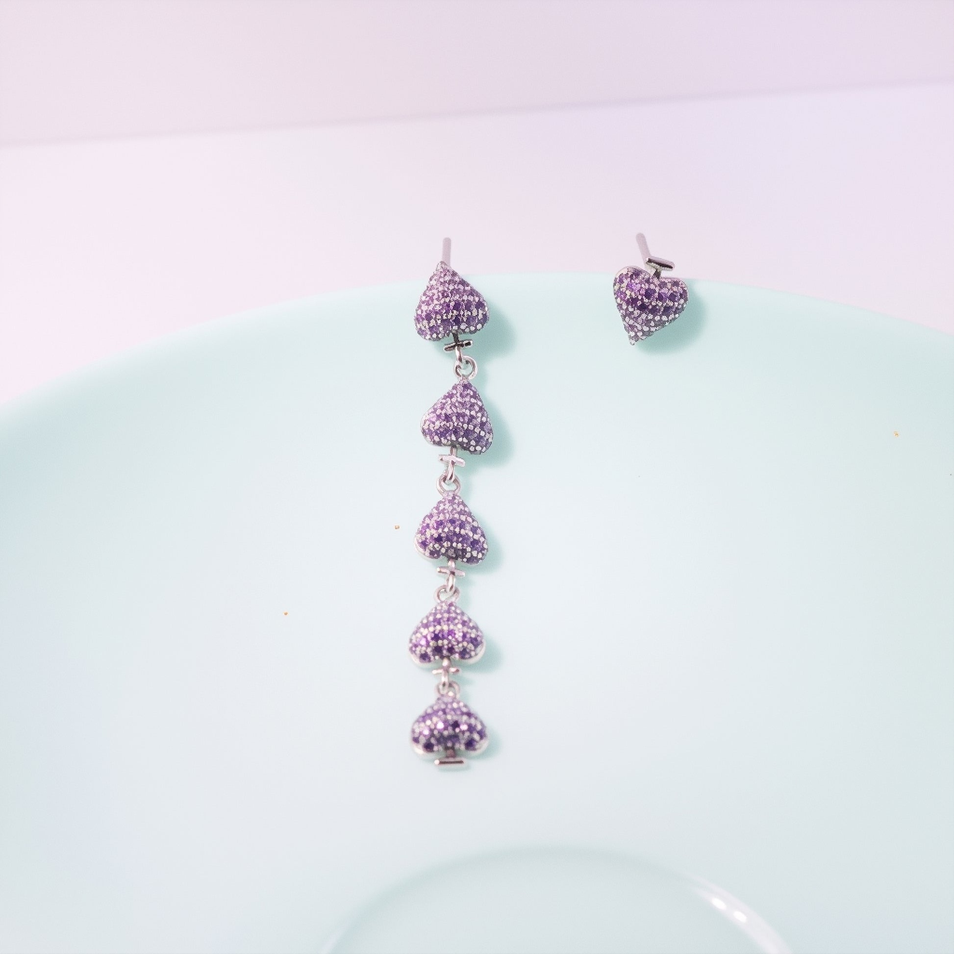 Gold plated asymmetric heart dangle earrings with zircon clusters, showcasing one solid heart and one clustered heart design on a model.