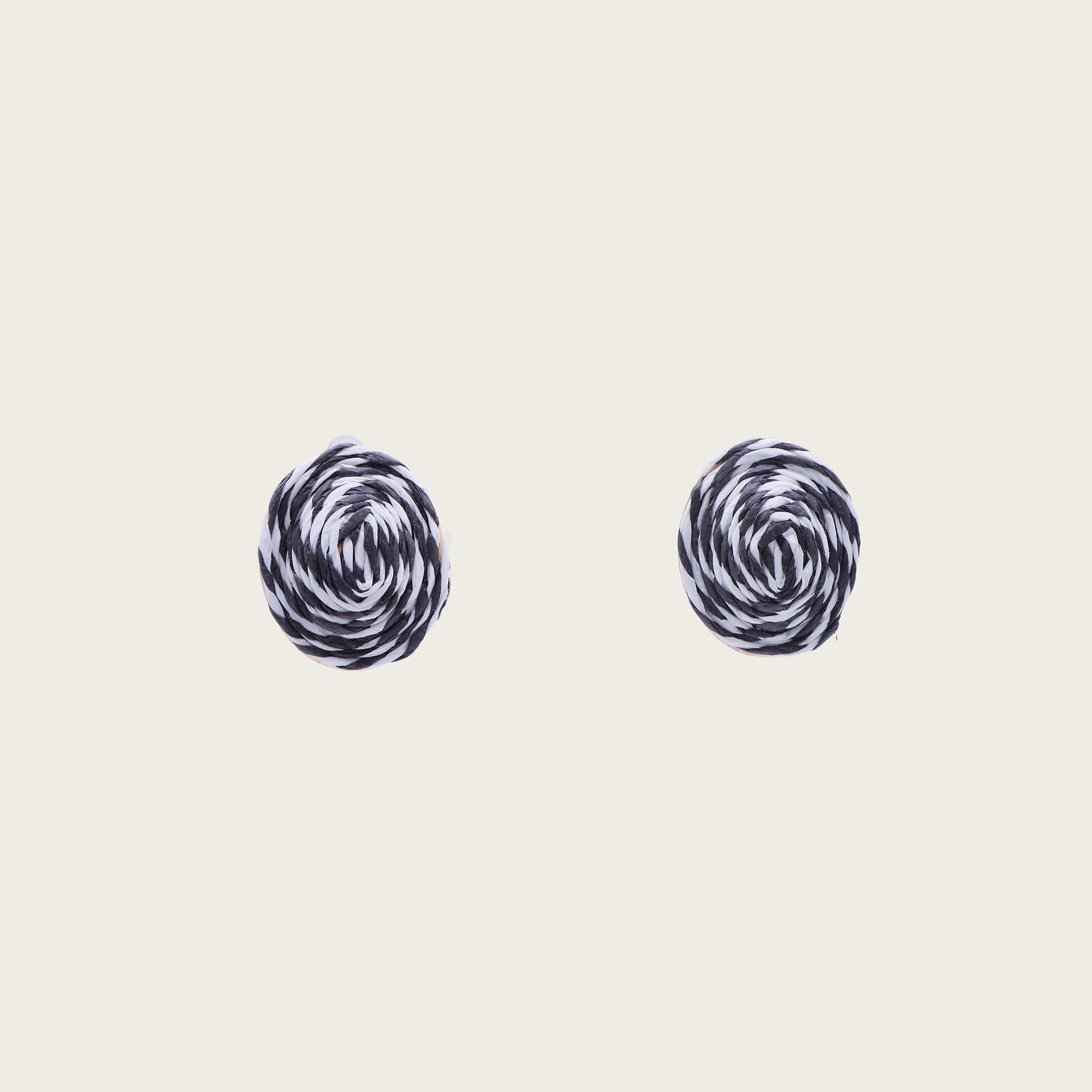 Close-up of circular black and white rattan stud earrings with intricate woven texture