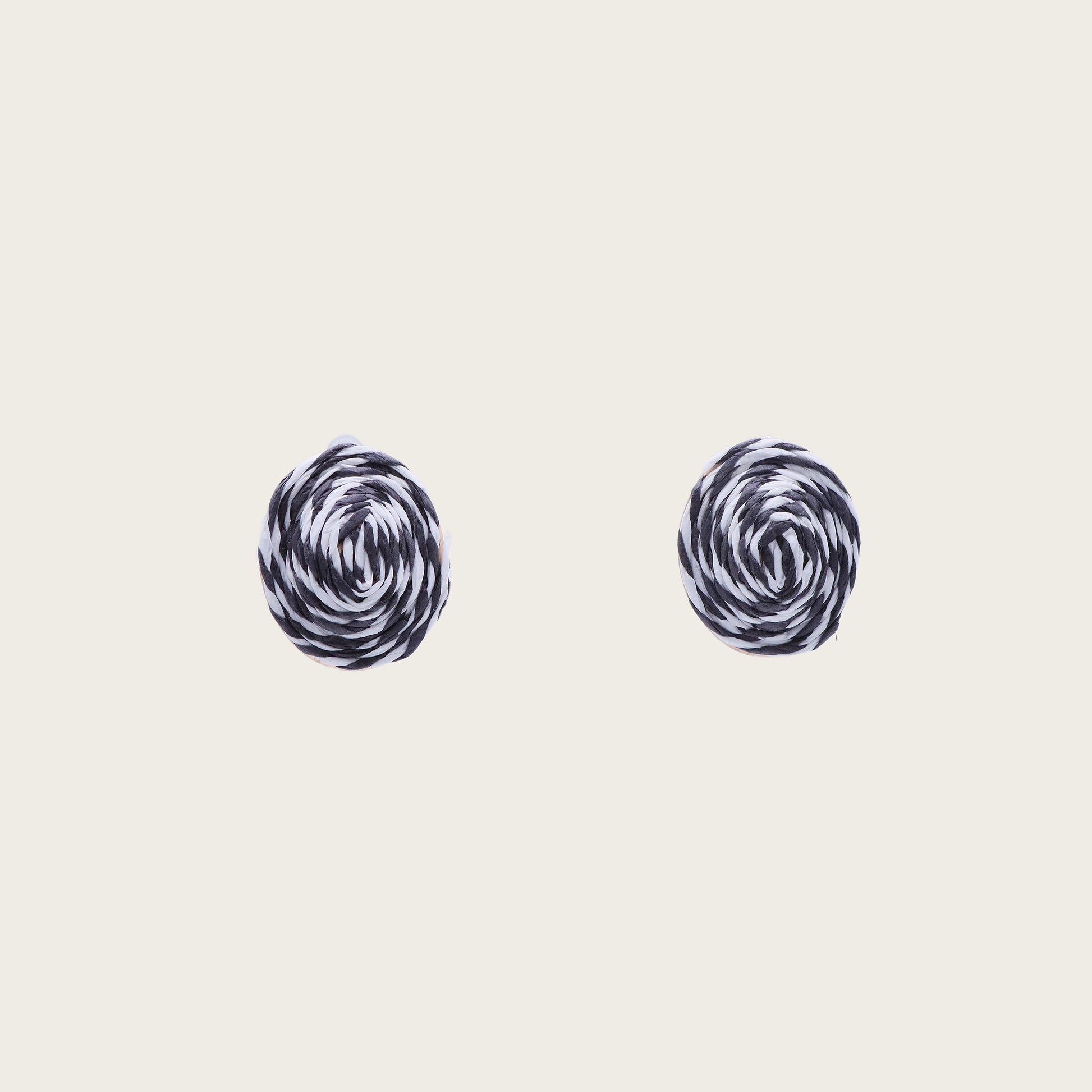Close-up of circular black and white rattan stud earrings with intricate woven texture