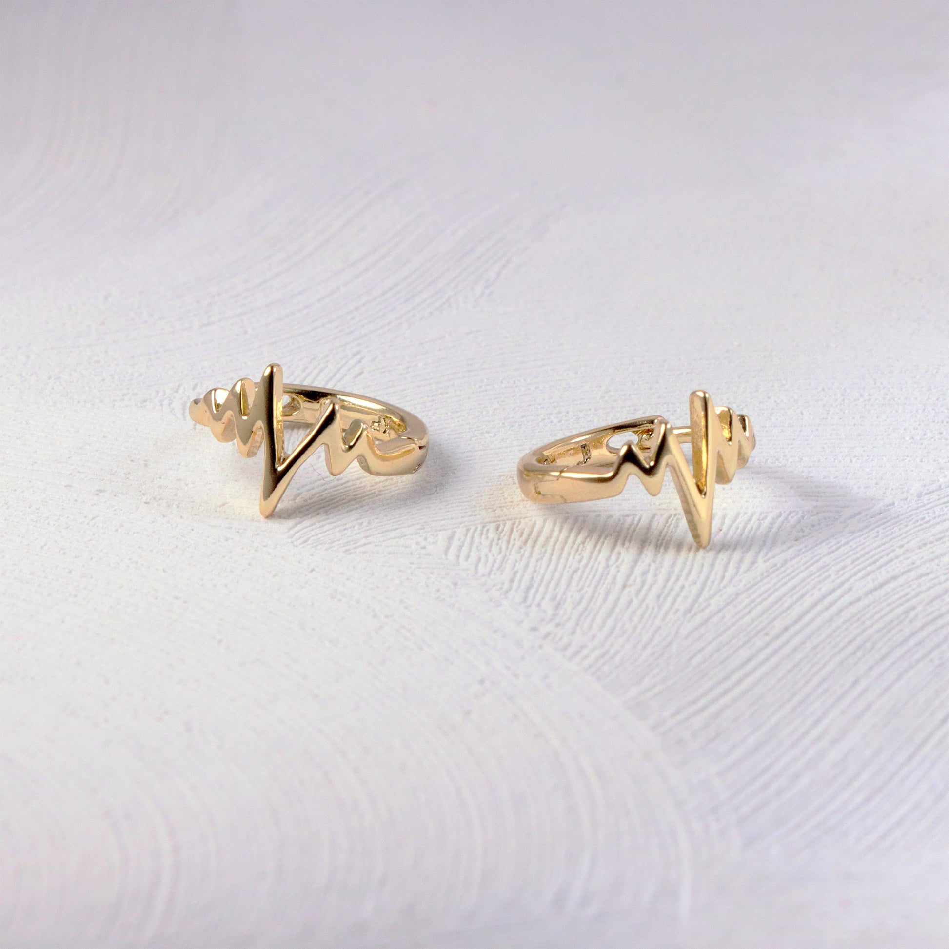 14K gold huggie hoop earrings with a horizontal heartbeat line engraving