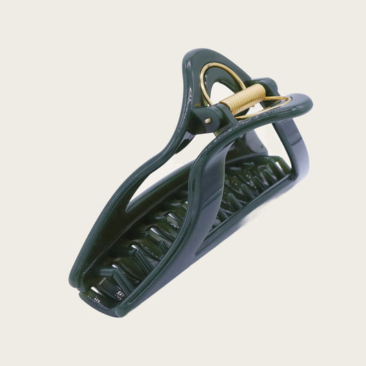 Oversized matte green hair claw clip with leaf-like texture, holding a voluminous blonde bun against dark hair.