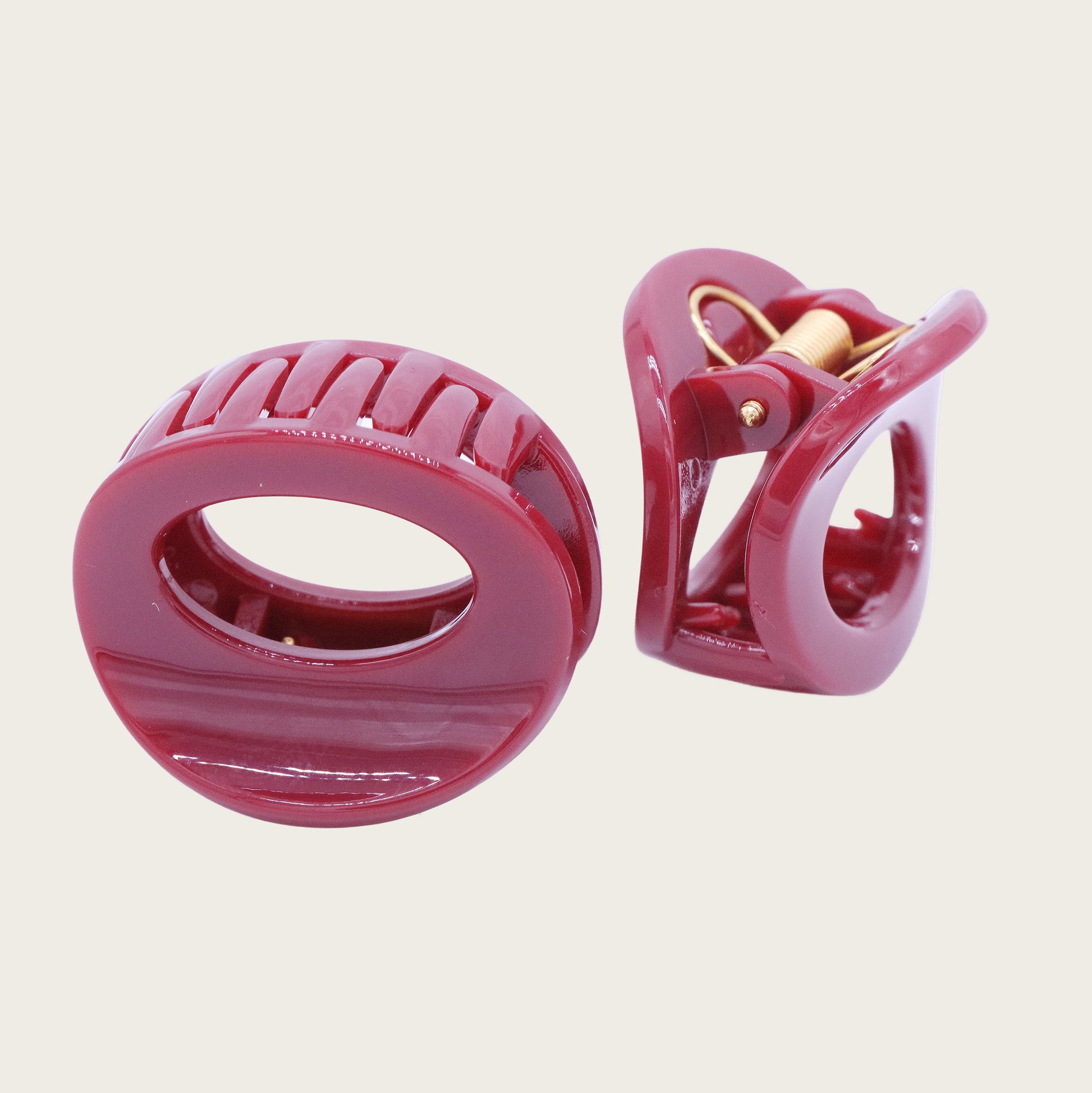 Petite oval hair claw clip in beige, holding a twisted section of blonde hair against a neutral background.