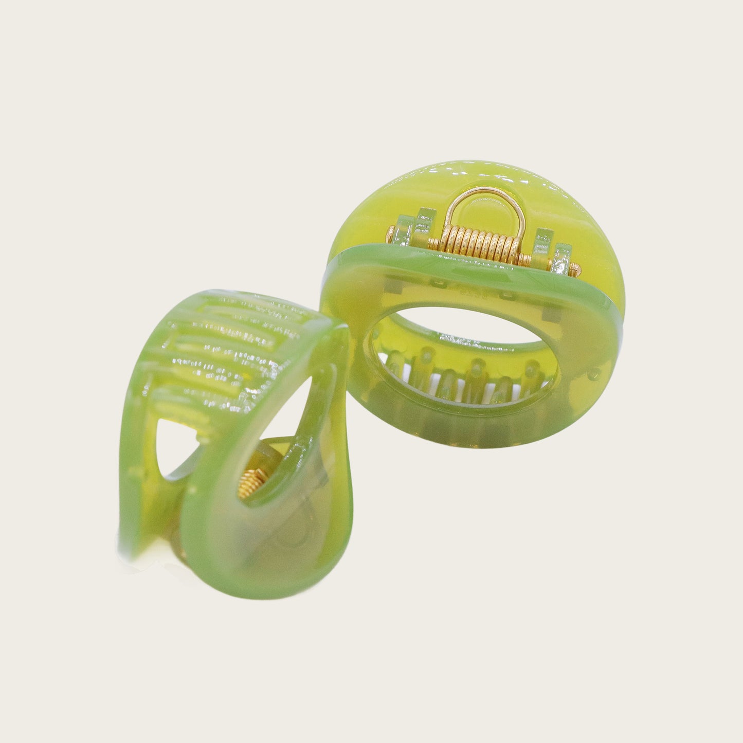 Petite oval hair claw clip in beige, holding a twisted section of blonde hair against a neutral background.