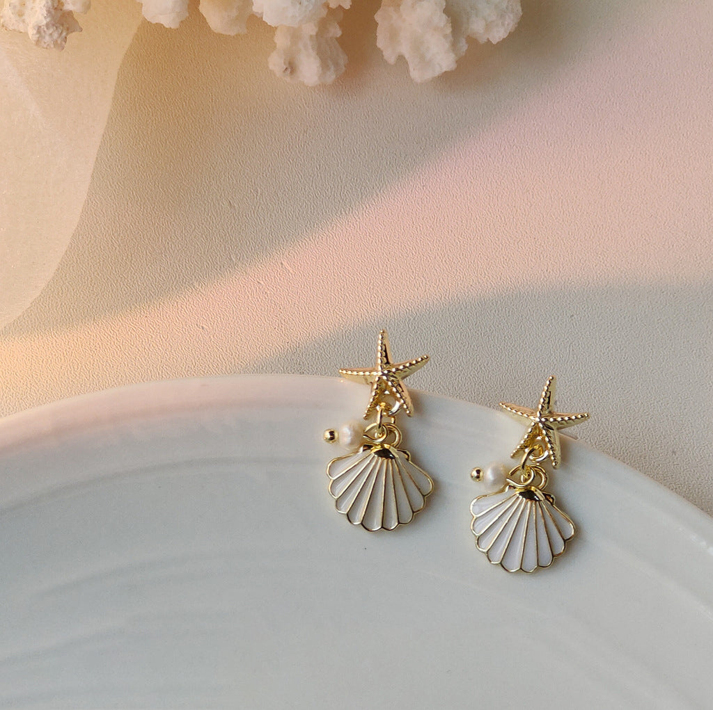 Delicate starfish earrings featuring a pearl drop.