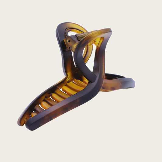 Angled view of tortoiseshell loop hair clip with marbled pattern, holding a textured ponytail with soft curls.