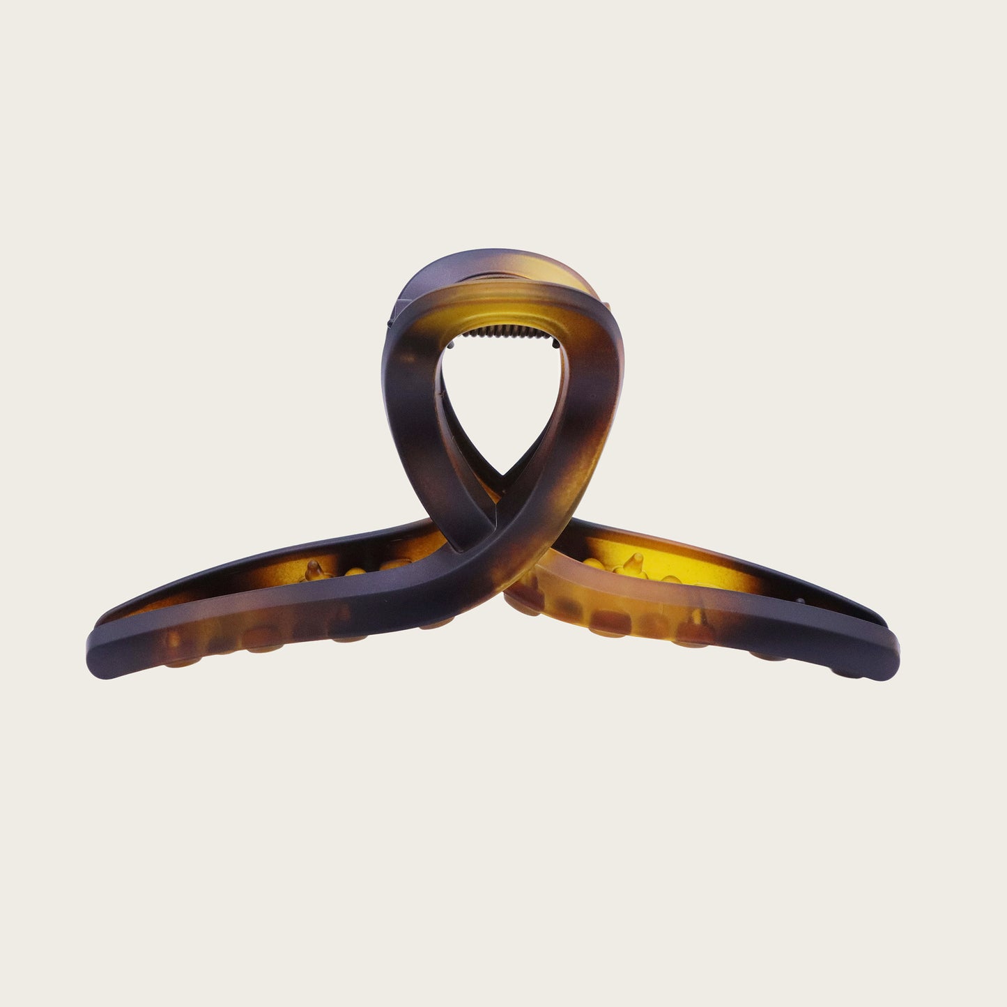 Angled view of tortoiseshell loop hair clip with marbled pattern, holding a textured ponytail with soft curls.