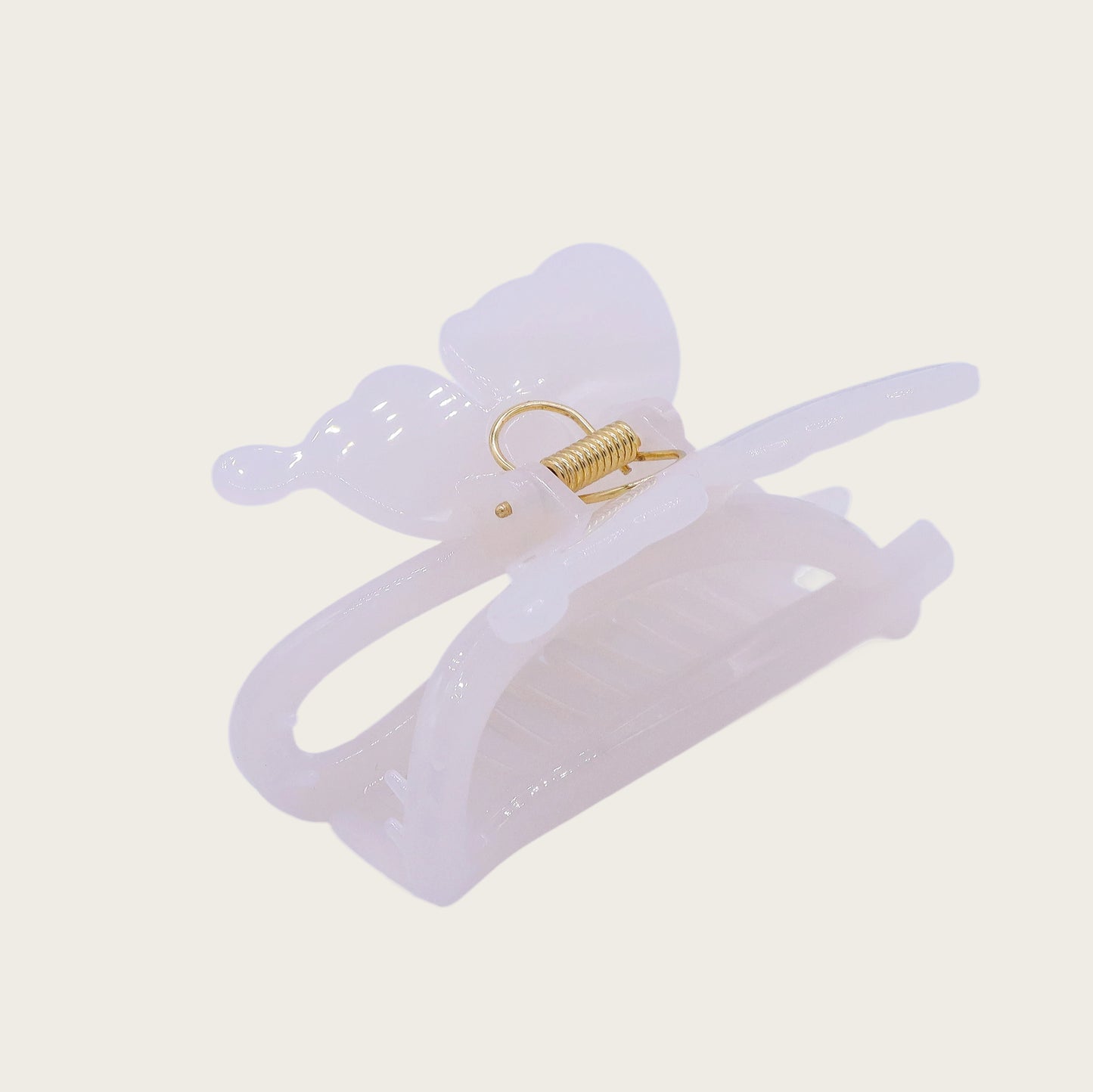 White marble-effect butterfly claw clip with translucent veining, securing a twisted updo against brunette hair in sunlight.