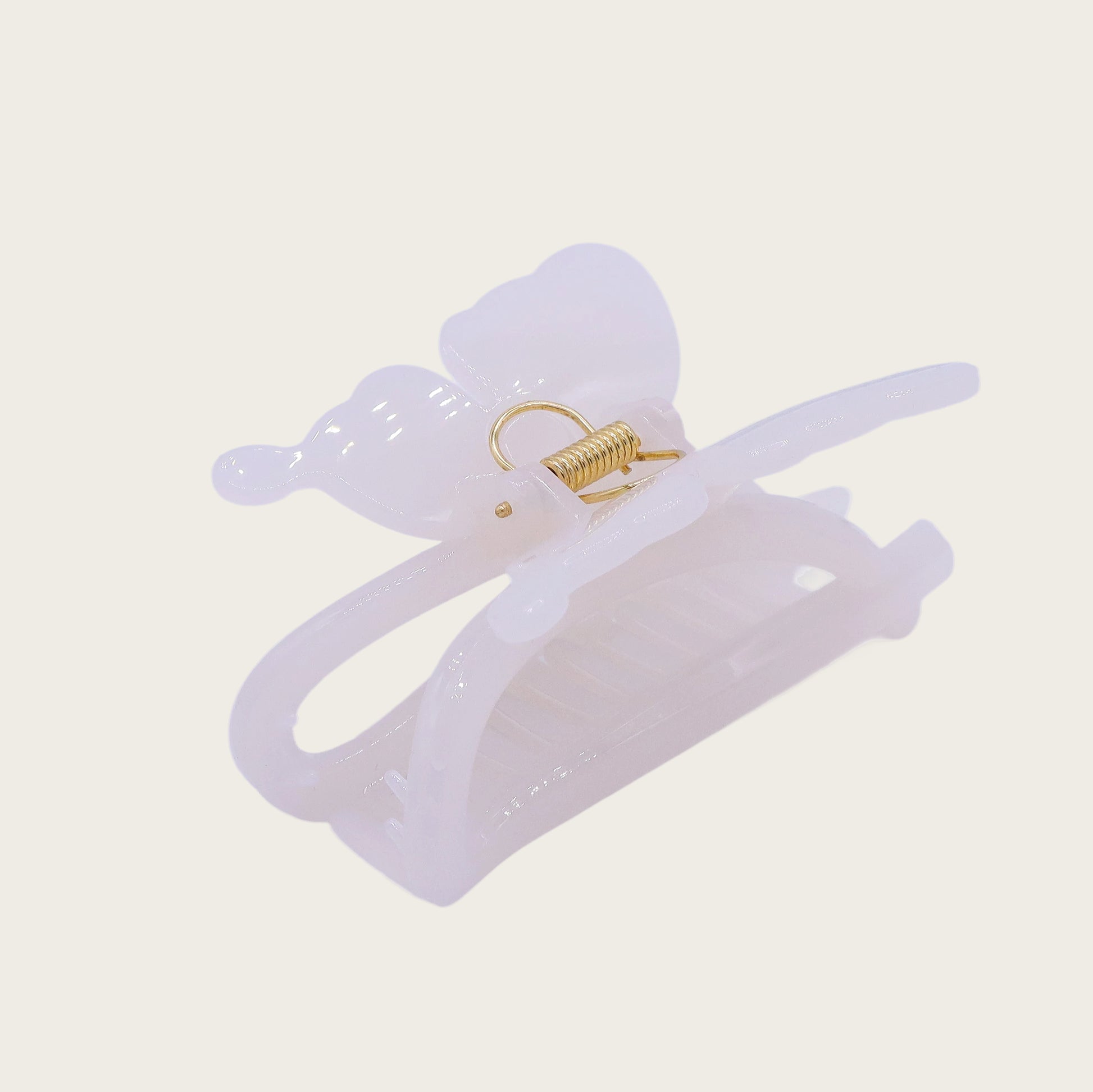 White marble-effect butterfly claw clip with translucent veining, securing a twisted updo against brunette hair in sunlight.