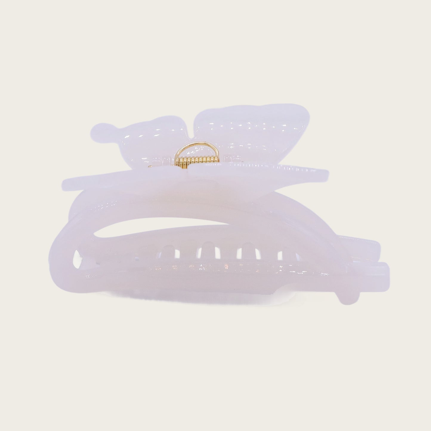 White marble-effect butterfly claw clip with translucent veining, securing a twisted updo against brunette hair in sunlight.