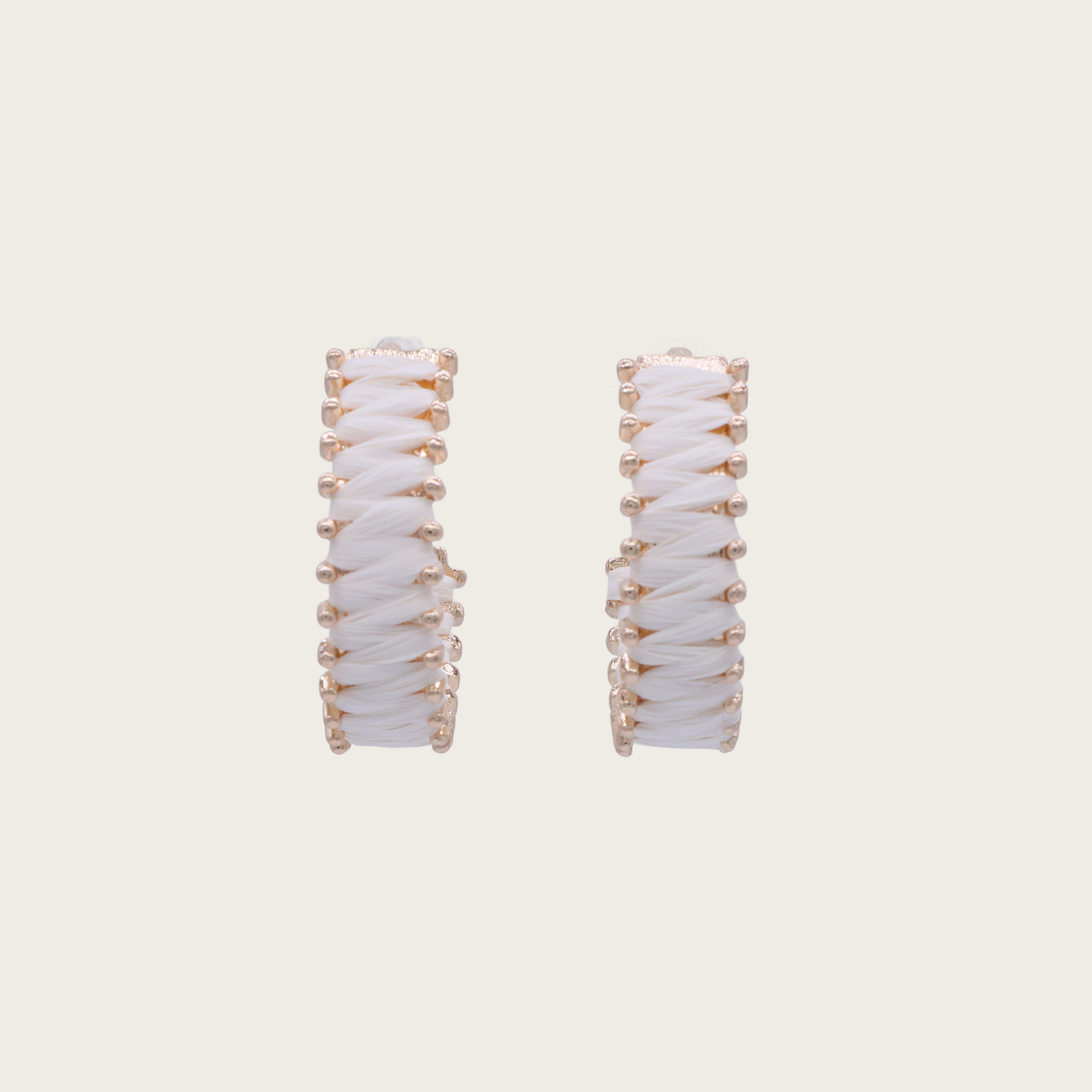 Close-up of circular woven rattan earrings with brass accents, modeled on a woman with tousled beach waves.